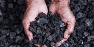 Coal mining - coal miner in the man hands of coal background. Picture idea about coal mining or energy source, environment protection. Industrial coals. Volcanic rock.